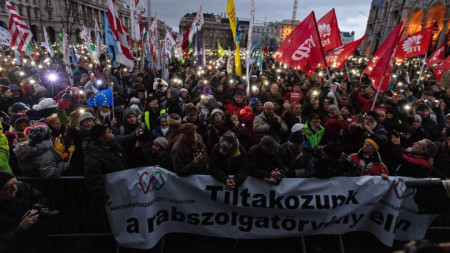 Демонстранти в Будапеща държат плакат с надпис „Протестираме срещу робския закон“.