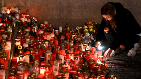 Опечалени поднасят цветя и свещи пред сградата на Философския факултет на Карловия университет в центъра на Прага, Чехия, събота, 23 декември 2023 г.