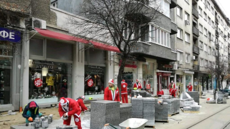 Работници, облечени като Дядо Коледа, редят плочки по столичната улица „Граф Игнатиев“.