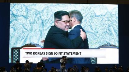 Журналисти гледат на голям екран как Ким Чен-ун и Мун Дже-ин се прегръщат след подписване на общата декларация.